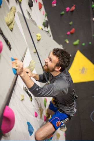 Male on the climbing wall looking up towards the top