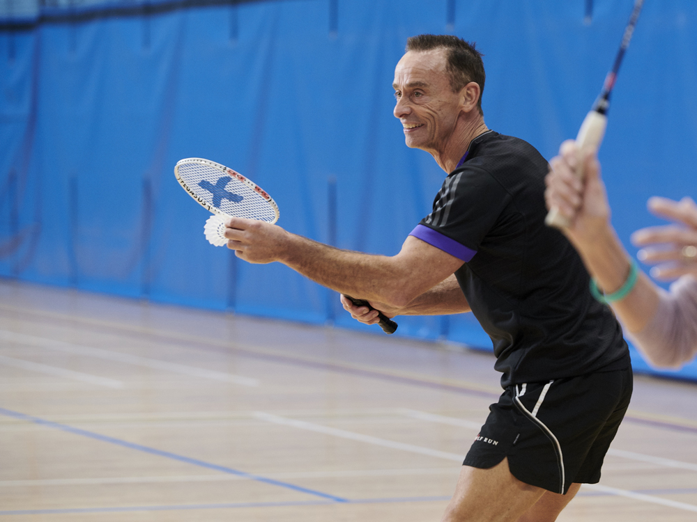 Man playing badminton holding a shuttlecock facing towards the camera