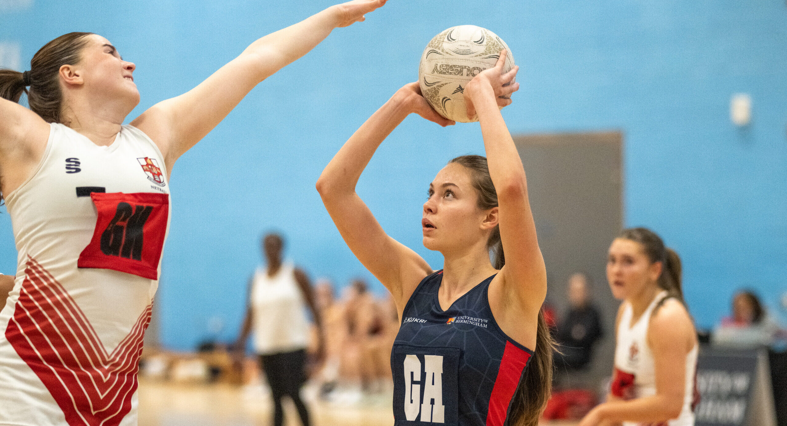 Goal Attack holding up ball whilst defender marks the shot.