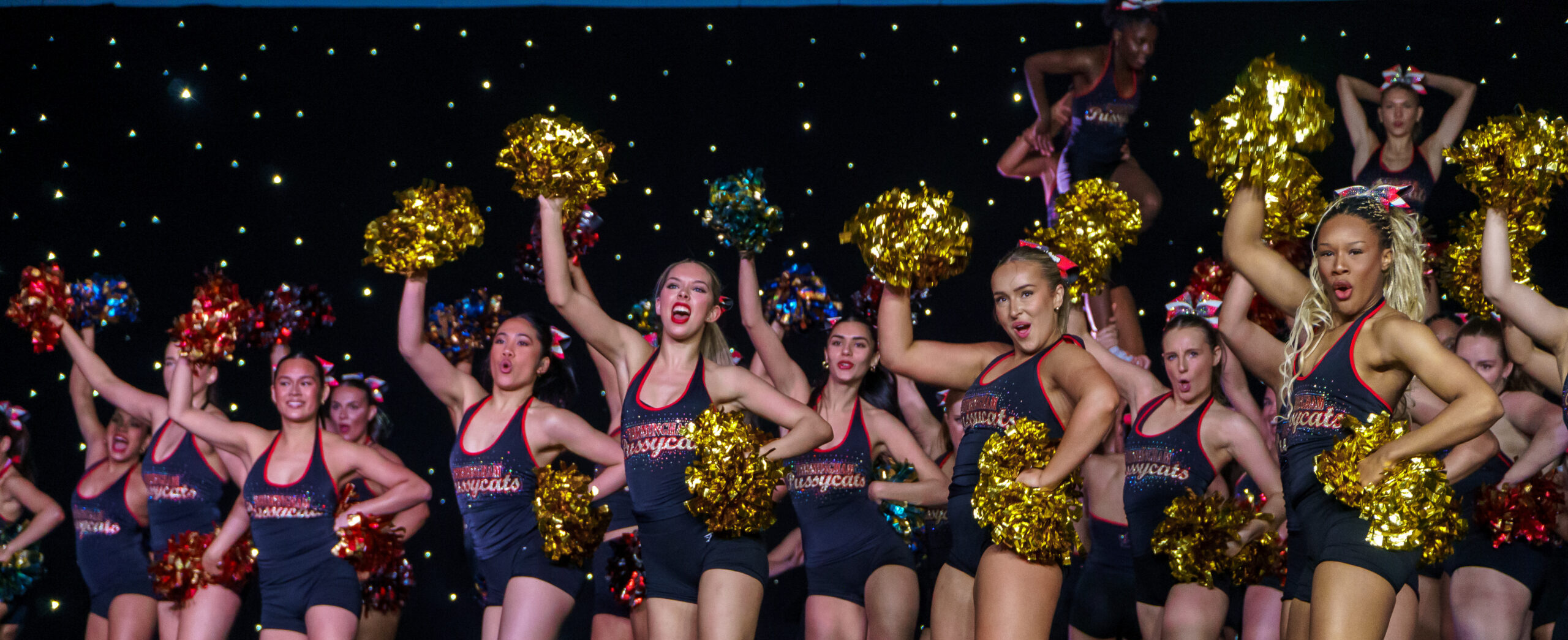 Birmingham Pussycats, the University of Birmingham cheerleaders, during their routine in a group raising their pom-pom in the air