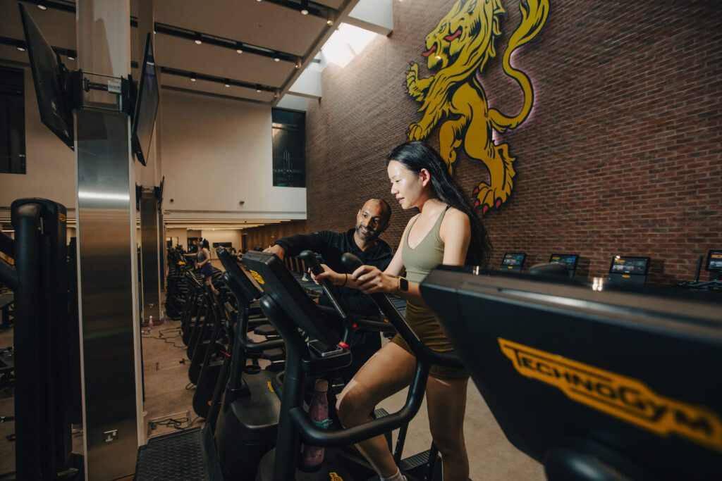 A member in Sport & Fitness gym getting support from a member of the gym team.