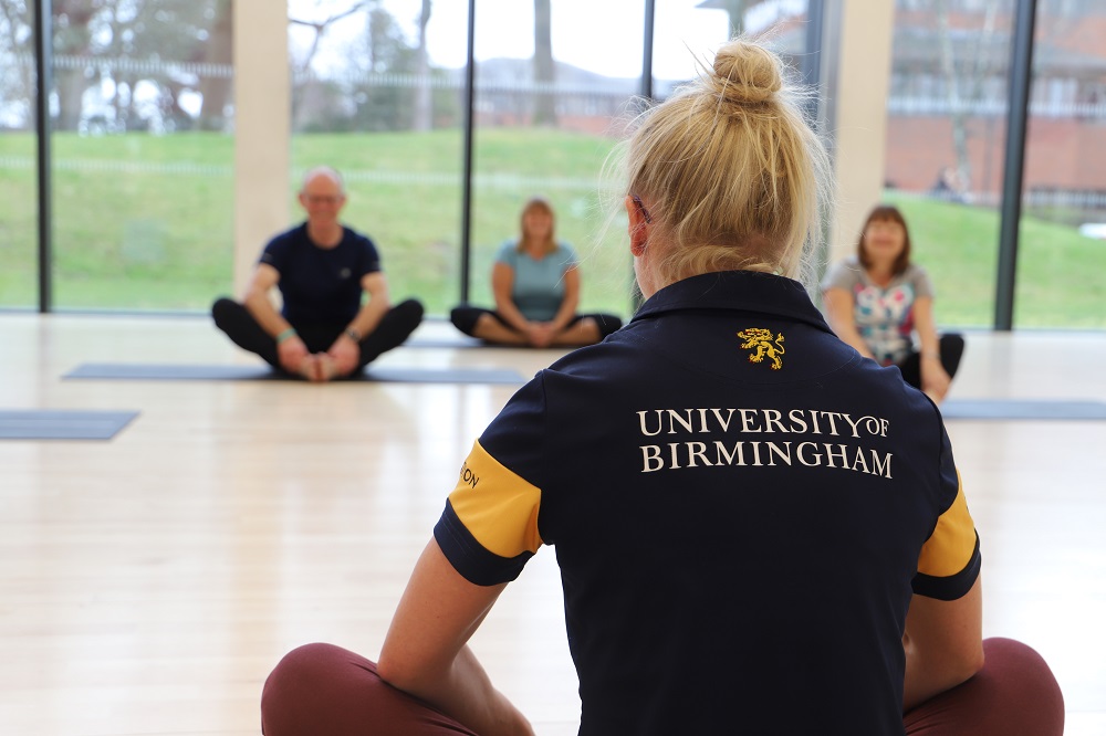 Yoga class in the Dojo with instructor Helen and three members sat cross-legged on the floor.