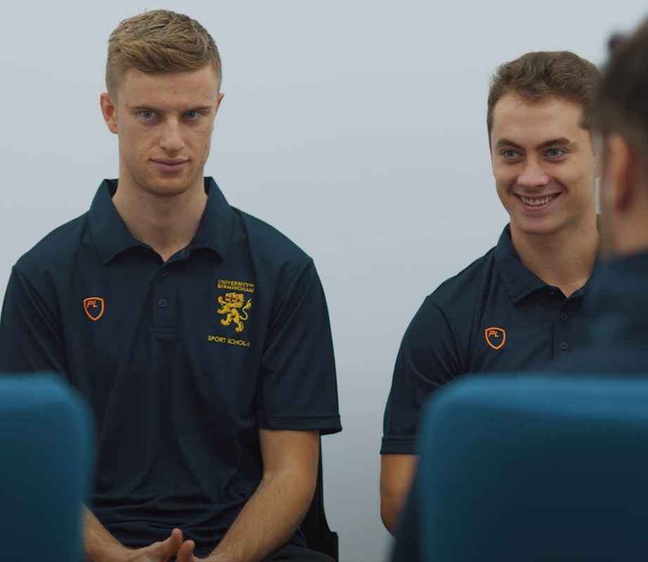 two sports scholars wearing blue t-shirts looking towards the camera