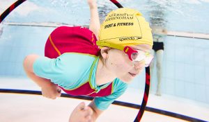 female swimming underwater through a hoop