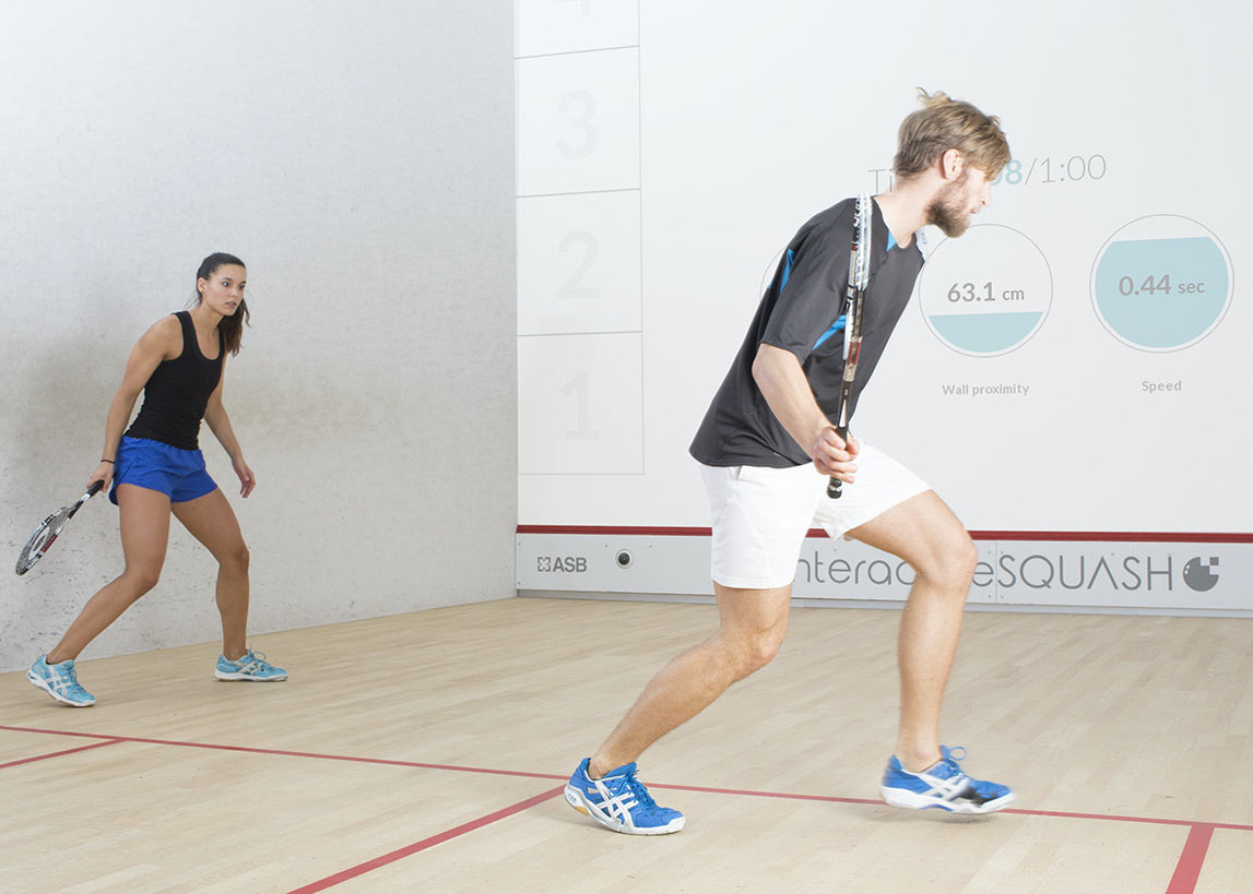 male and female playing squash against an interactive wall