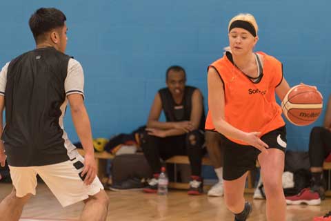 Woman dribbing a basketball past a male on court