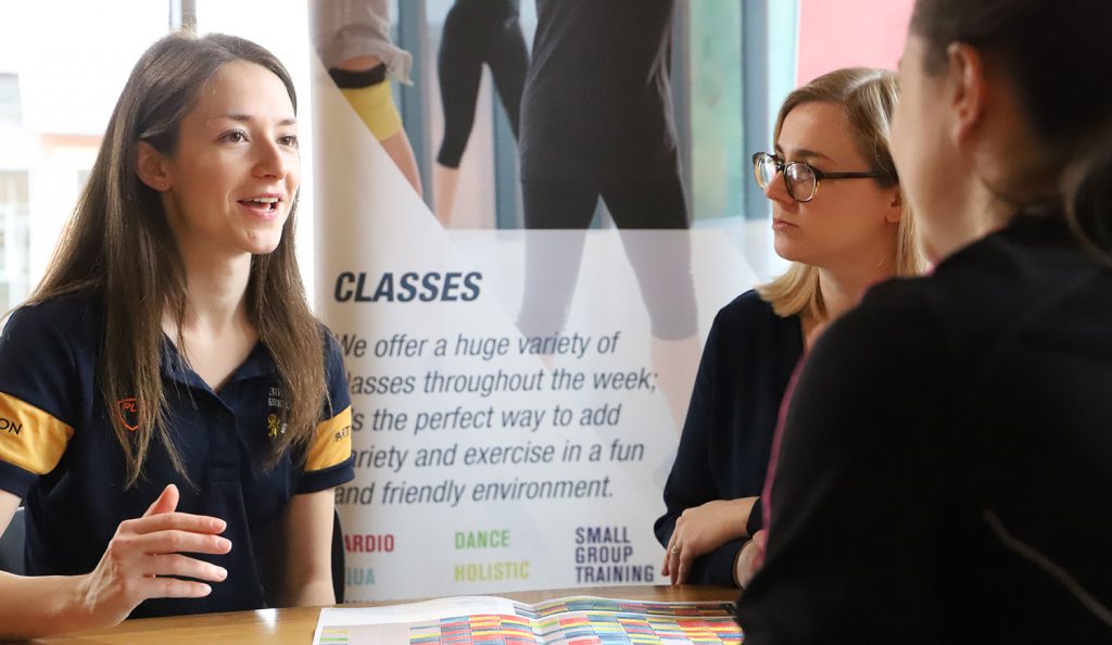 Two members sat at a table listening to a female instructor in a class consultation