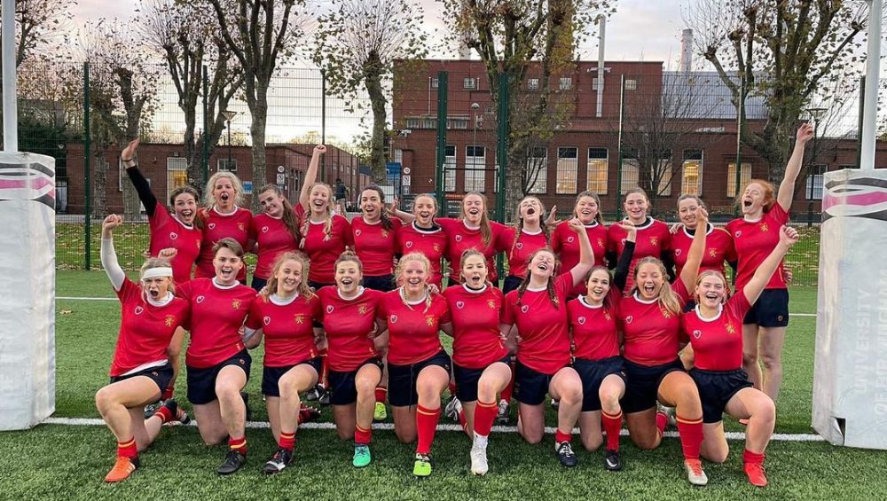 The women's rugby team pose for a celebratory team photo between the rugby posts at University of Birmingham