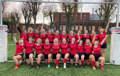 The women's rugby team pose for a celebratory team photo between the rugby posts at University of Birmingham