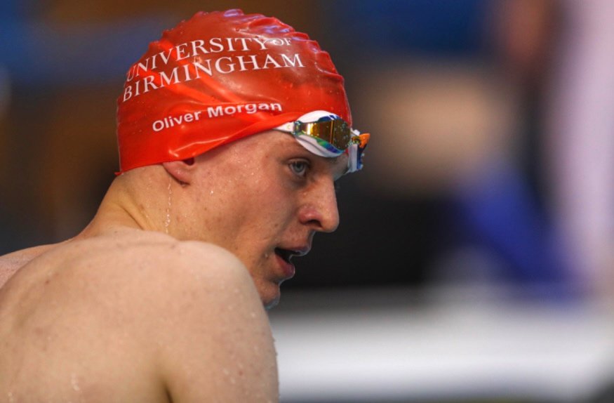 Oliver Morgan looking towards the camera with a red swimming hat on