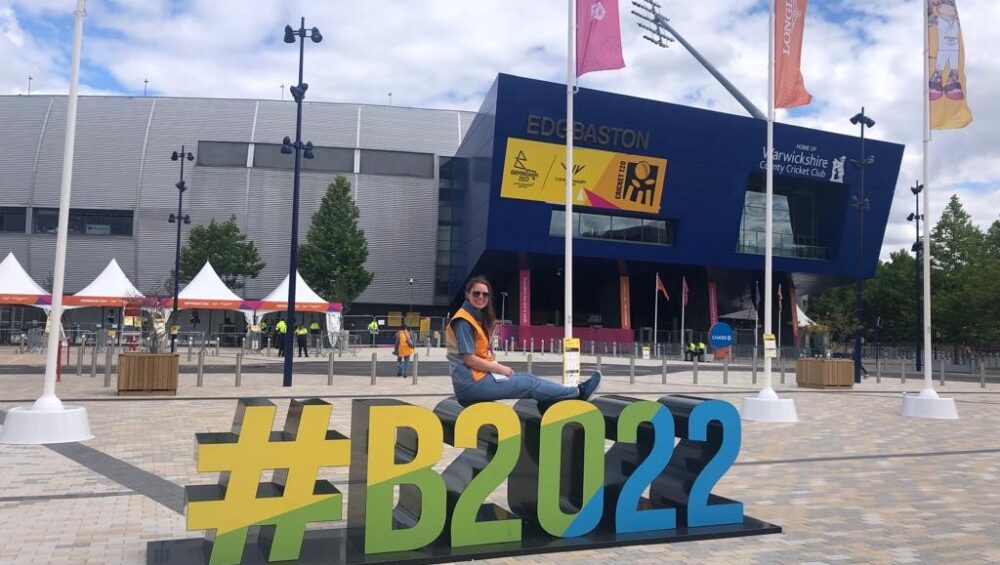 Volunteer Becki sits on giant letters spelling #B2022