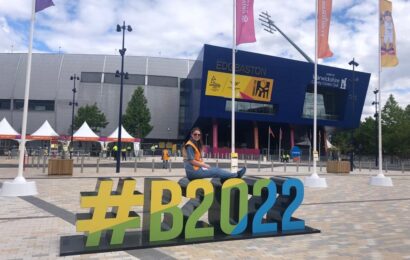 Volunteer Becki sits on giant letters spelling #B2022