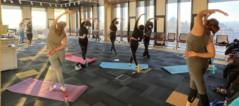 Image of students taking part in sunrise yoga session on the top floor of the main library