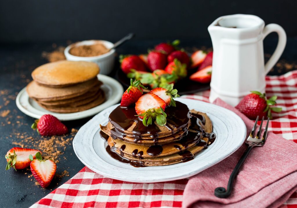 Pancakes drizzled in chocolate sauce and topped with strawberries