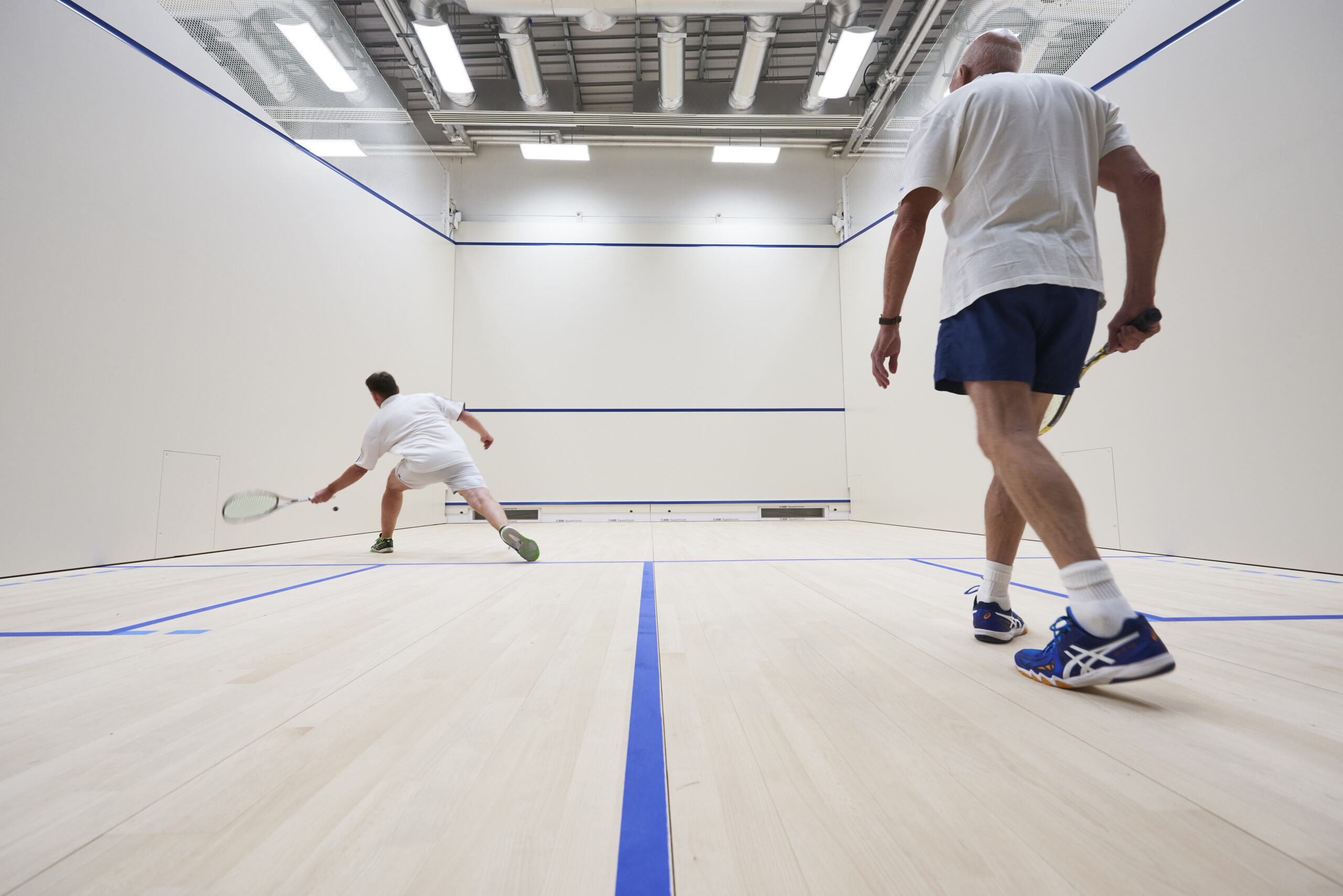 Two members of UoB Sport & Fitness playing squash in our glass-back squash courts.