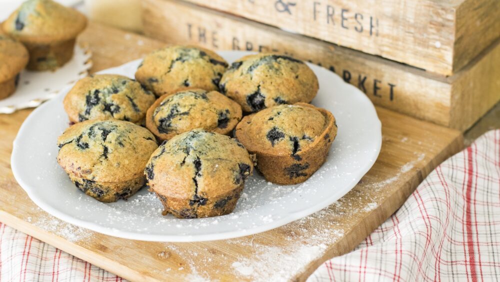 7 blueberry muffins on a plate dusted with icing sugar