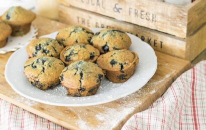 7 blueberry muffins on a plate dusted with icing sugar