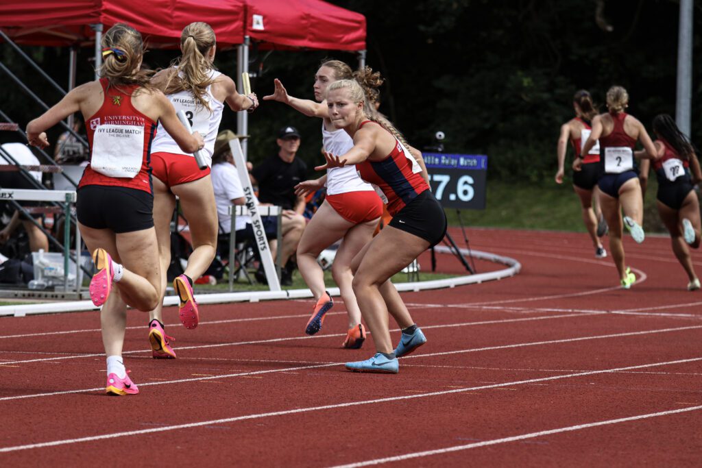 Women's Relay team passing the baton while running