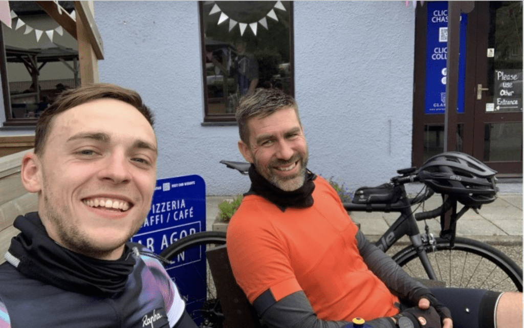 Selfie of Kacper and Ross sat down next to bike