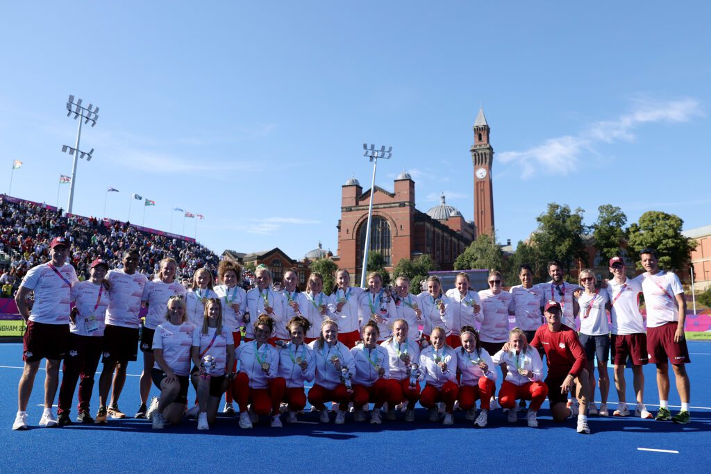 Hockey winners posing with medals on hockey pitches