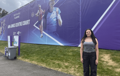 Georgia standing on the right hand side of large banner promoting Rothesay Classic Tennis event