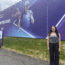 Georgia standing on the right hand side of large banner promoting Rothesay Classic Tennis event
