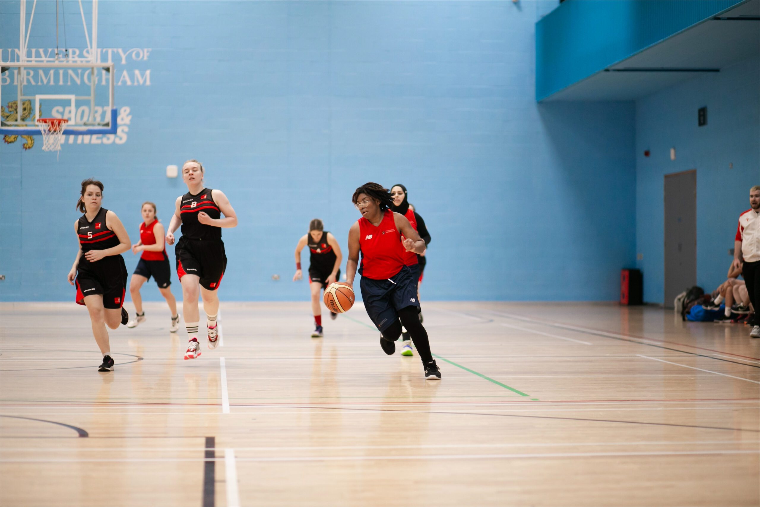 A basketball player dribbling down court in the Munrow Arena in Sport and Fitness on the Edgbaston campus