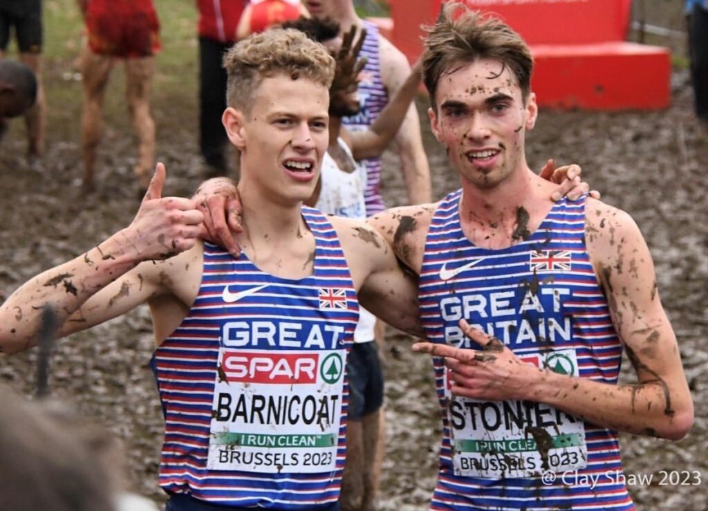 Two runners, with their thumbs up, covered in mud.