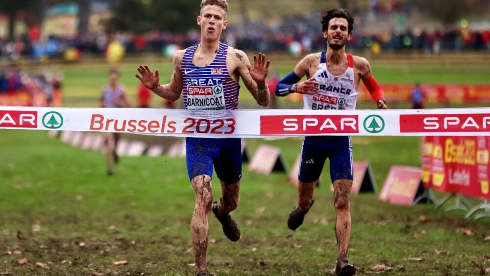 Will Barnicoat running through the finish line, covered in mud.