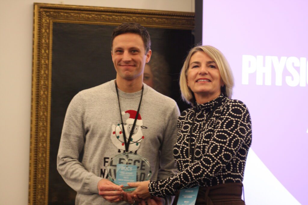 Chris pictured holding trophy alongside award. presenter