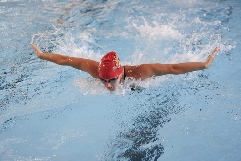 Student swimming with arms out