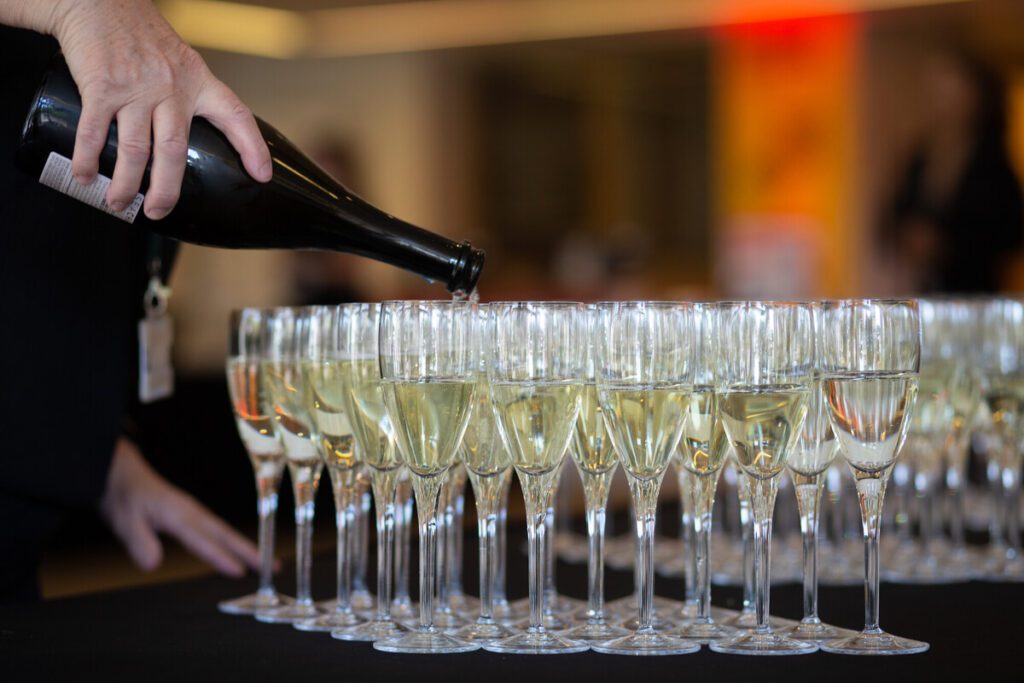 Glasses of champagne on a table with someone pouring drinks.