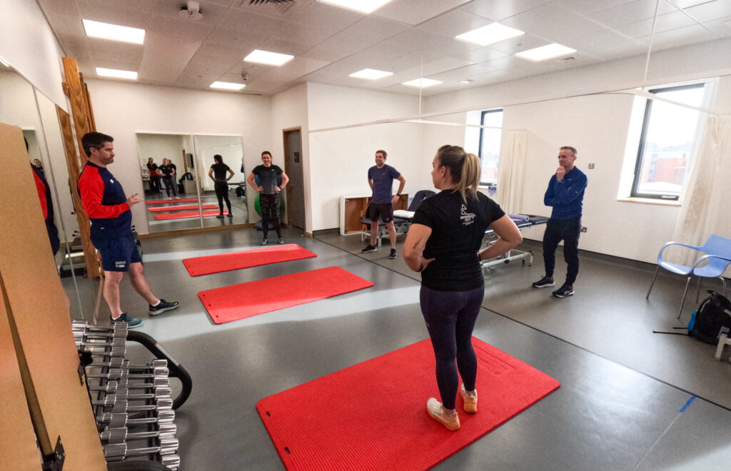 Umpires taking part in a physical activity on mats.