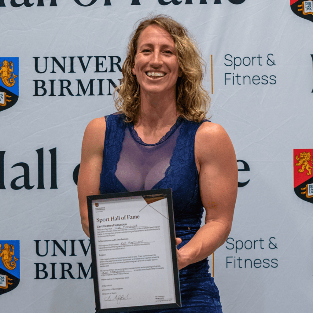 Kat Merchant smiling holding Hall of Fame certificate