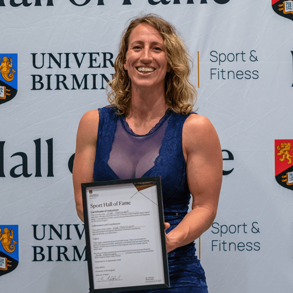 Kat Merchant smiling holding Hall of Fame certificate.