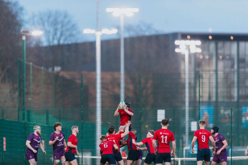 Rugby Union team in New Balance kit holding ball in the air