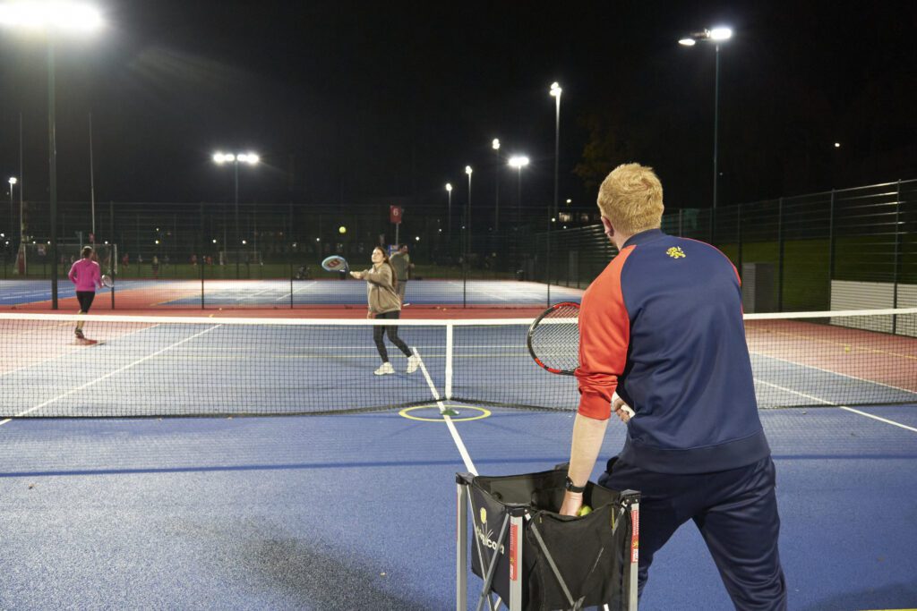 Tennis coordinator throwing tennis balls at participants