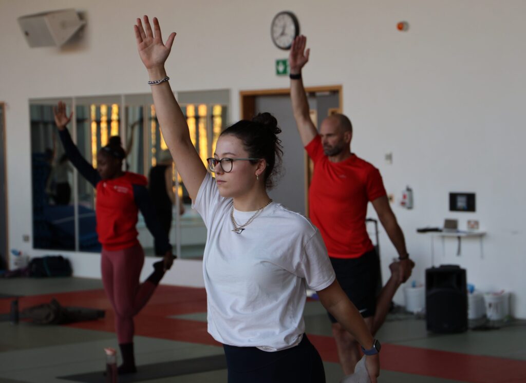 Hatha yoga session - participants holding leg up whilst other hand points towards the ceiling