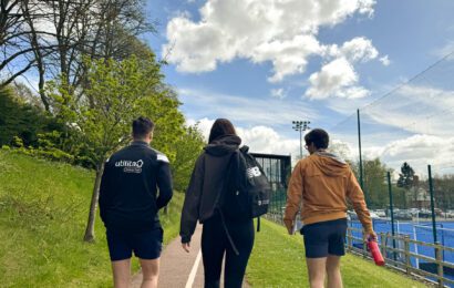 Trio walking alongside the outdoor courts