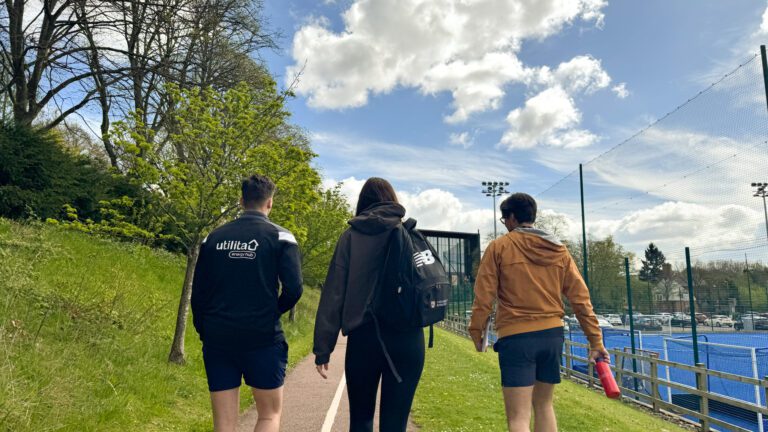 Trio walking alongside the outdoor courts