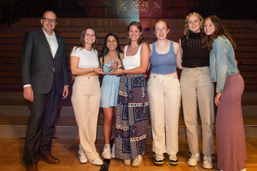 Sports club holding medal on stage