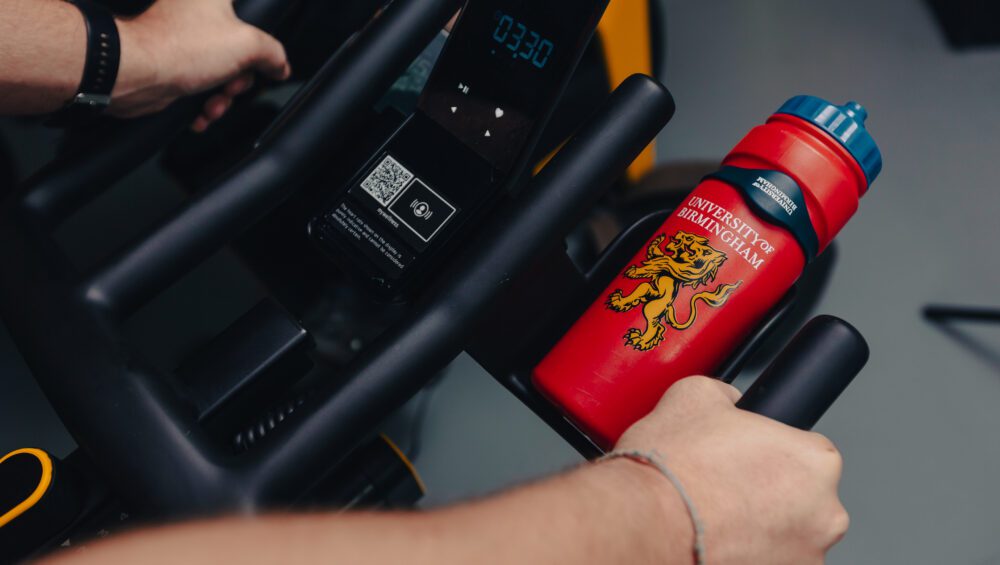UB Sport branded water bottle in bottle holder on exercise bike