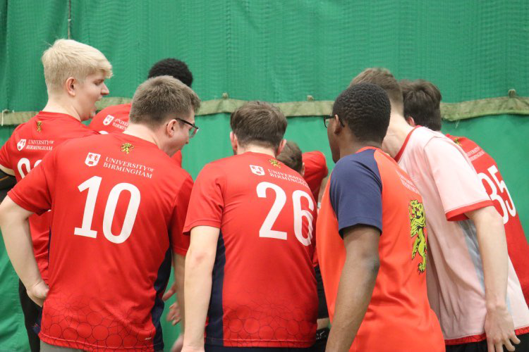 Dodgeball team grouping together in a huddle cheering before the game