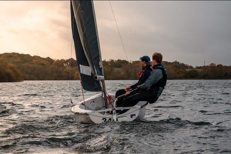 Two members of the Sailing club on a sailing boat, on the water.
