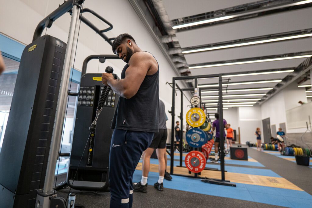 Member pulling the cables on the resistance machine up to their chest.