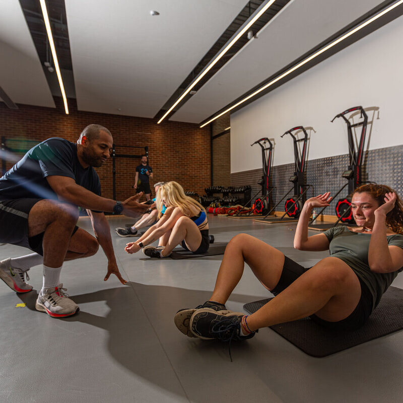 Gym instructor supporting a member in a group session.