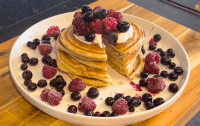 Pancakes on a plate with berries on the top and around the plate