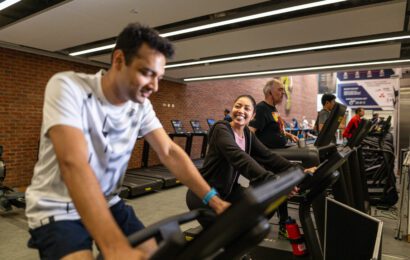 Man and woman on a bike in the gym, smiling