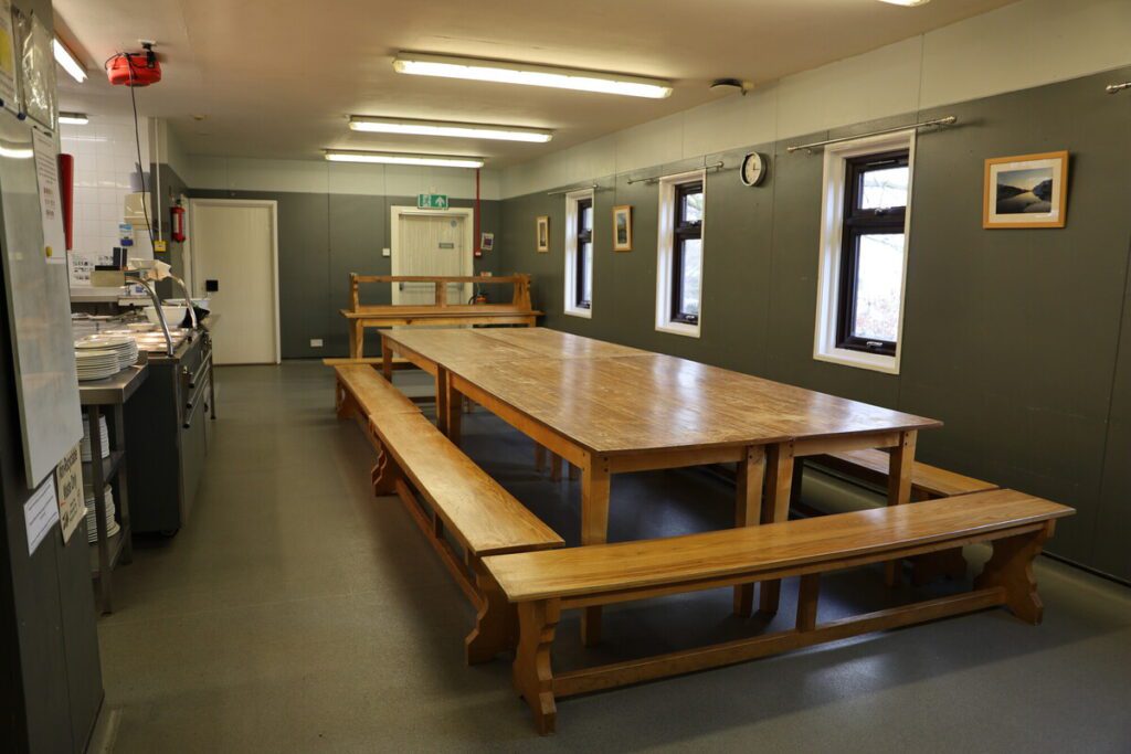 Lunchroom with a long table in the middle of the room and the kitchen on the left-hand side.