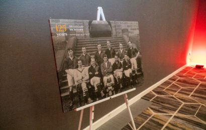 An image of a canvas printed with an old photo of the football team in black and white, balanced on an easel.